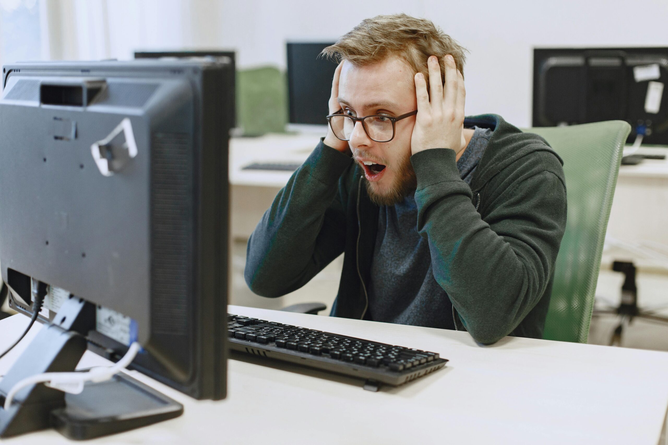 A man in his late 20s looking at his computer in shock after realizing these digital marketing myths