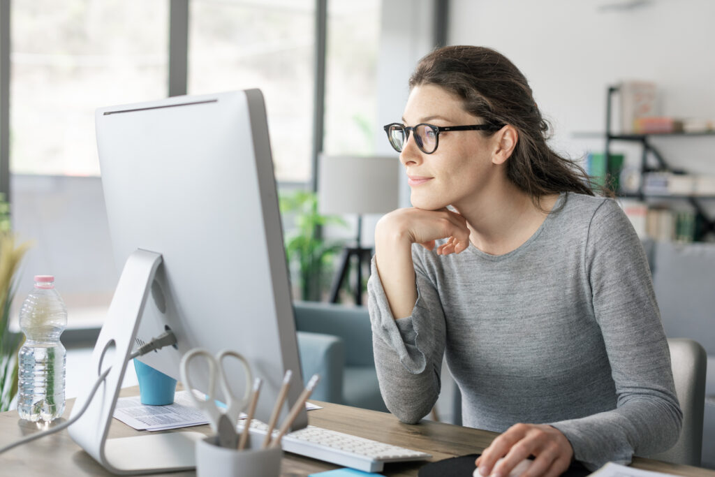 Woman analyzing ad copy on her computer screen while crafting a more compelling headline for a Google Ads campaign.