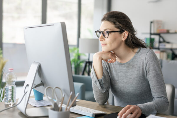 Woman analyzing ad copy on her computer screen while crafting a more compelling headline for a Google Ads campaign.