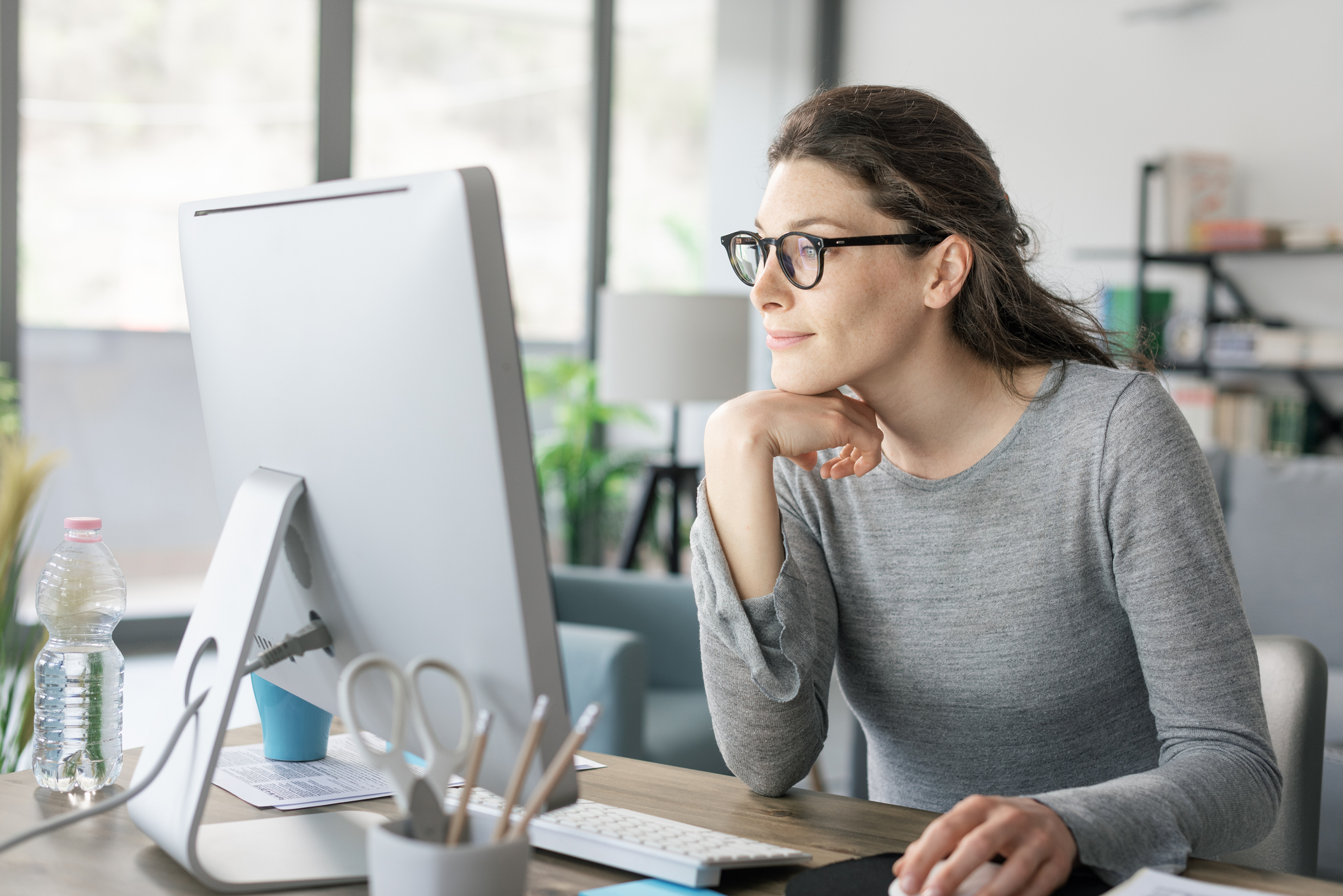Woman analyzing ad copy on her computer screen while crafting a more compelling headline for a Google Ads campaign.