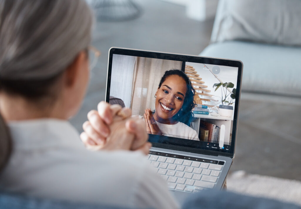 Mental health clinician using a laptop to record or host a virtual video session focused on supportive behavioral health communication