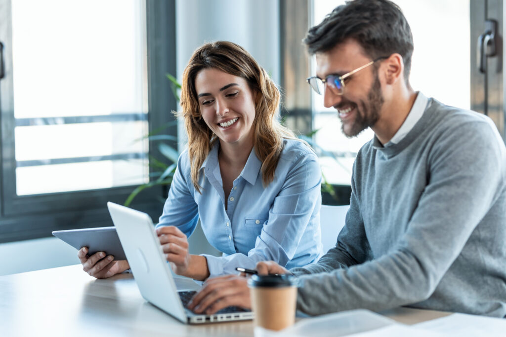 Two professionals working together in a modern office, reviewing digital marketing data that supports building a sustainable paid ads strategy for admissions teams.