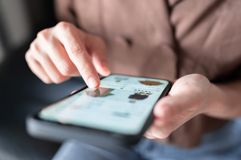 Woman shopping online on a smartphone after finding products through Google Ads for competitive ecomm.